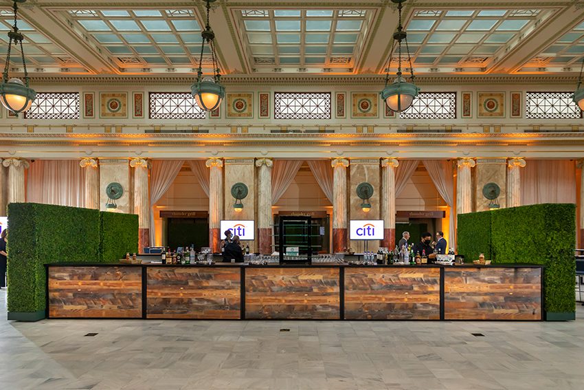Large Rustic Wooden Bar in East Hall featuring Green Hedge Walls on each side.