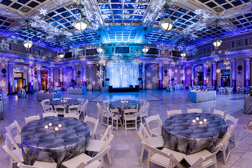 Winter Themed Event in East Hall featuring a Stage, Dance Floor, Blue Up-Lighting and White Snowflakes projected onto the walls.