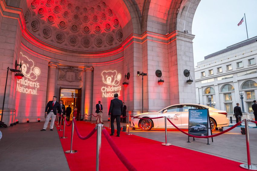 Presidential Suite Outdoor Entrance Customized for a Corporate Event; with Light Projected Branding, a Red Carpet, and Red Velvet Stanchions.