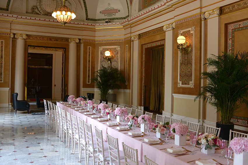 Pink and White Themed Seated Community Table with Floral Centerpieces in Presidential Suite.